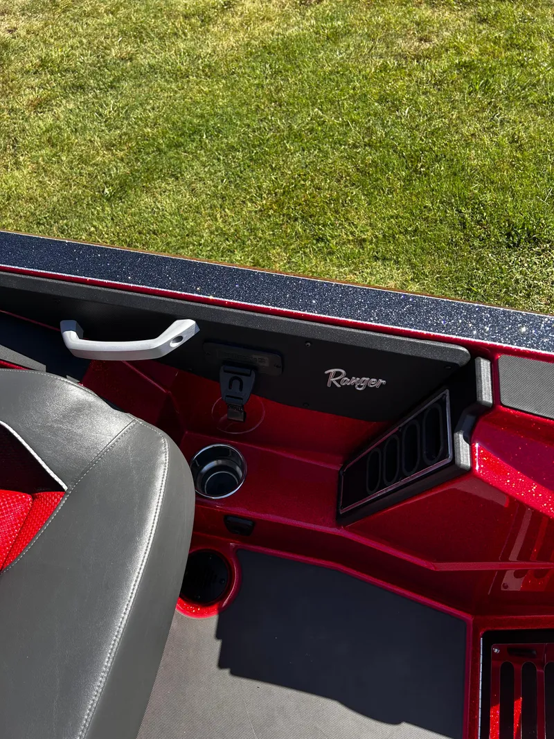 Slide: The Image of 2024 Ranger Z519 boat interior with red accents and black seat, on grass background. - 34