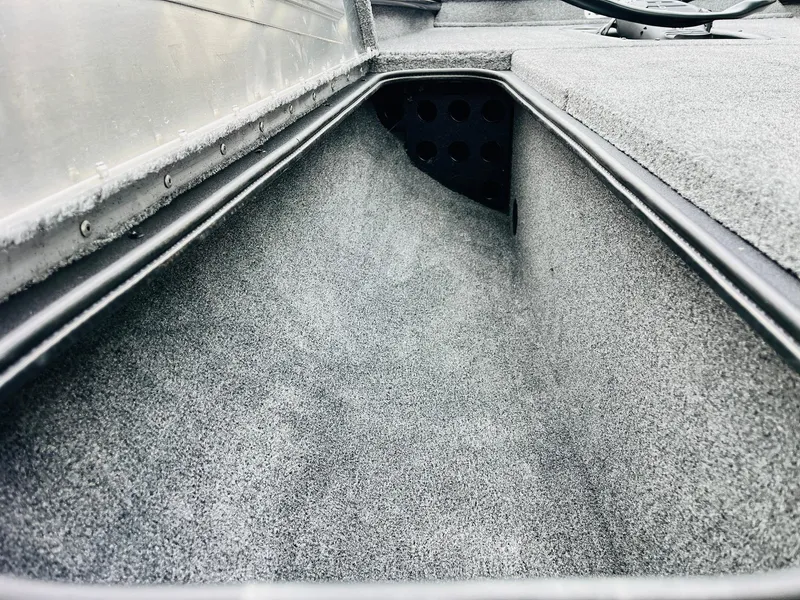 Slide: The Image of 2026 Tracker Pro Team 175 boat storage compartment, carpeted interior, close-up view. - 12