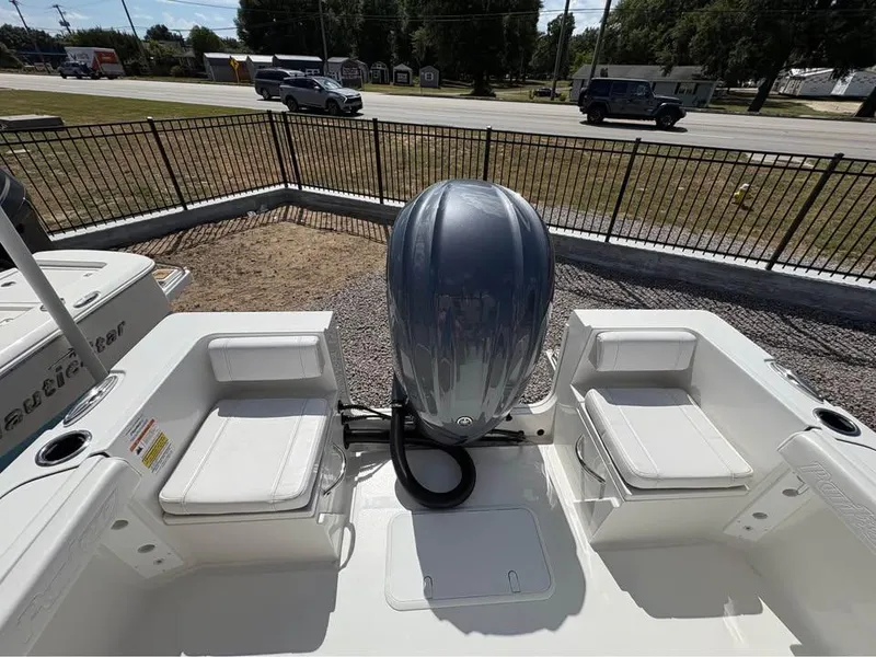 Slide: The Image of 2025 Parker 23SE Center Console boat with outboard motor and seating, parked near a road. - 11