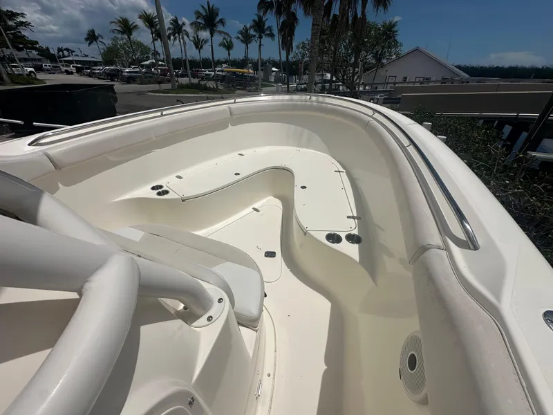 Slide: The Image of 2009 Pursuit C 310 Center Console boat interior with seating and cup holders, surrounded by palm trees. - 10