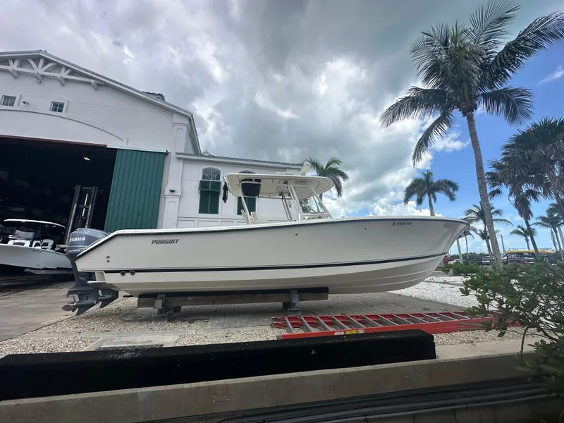 Slide: The Image of 2009 Pursuit C 310 Center Console boat on display near palm trees and a building. - 5