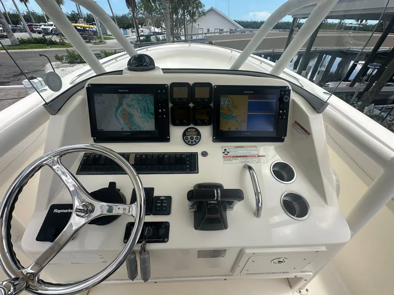 Slide: The Image of 2009 Pursuit C 310 Center Console boat dashboard with navigation screens and controls. - 9