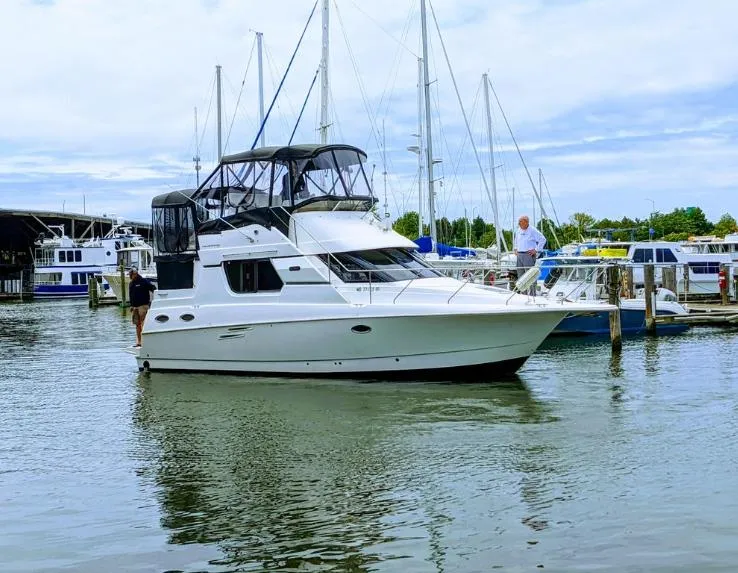 The Image of 1998 Silverton 322 Motor Yacht docked at a marina, surrounded by sailboats. - 0
