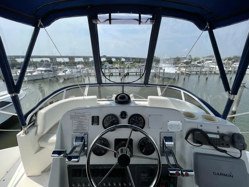 Slide: The Image of 1998 Silverton 322 Motor Yacht helm with marina view, featuring navigation instruments and steering wheel. - 4