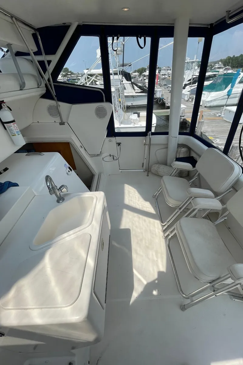 Slide: The Image of 1998 Silverton 322 Motor Yacht interior with seating, sink, and marina view. - 7