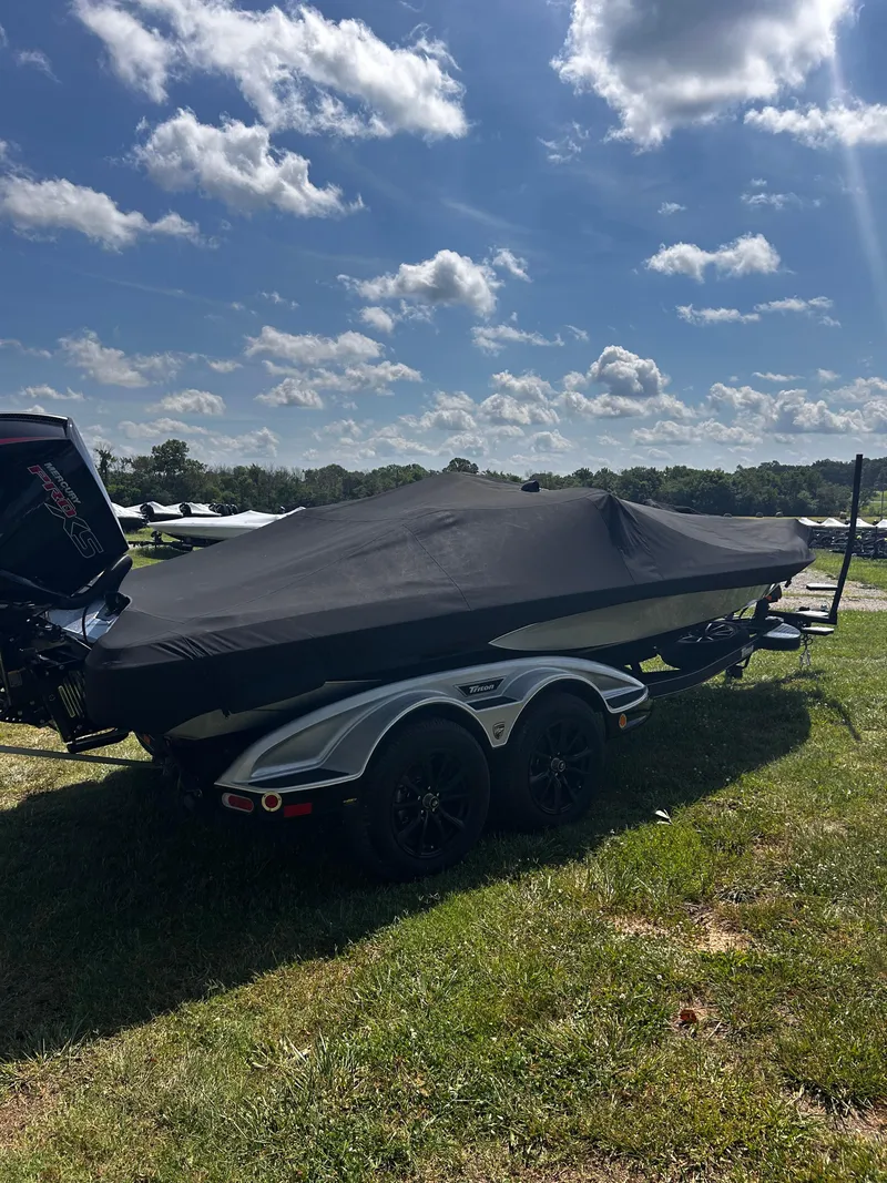 Slide: The Image of 2024 Triton 21XP boat covered, parked on grass under a partly cloudy sky. - 13