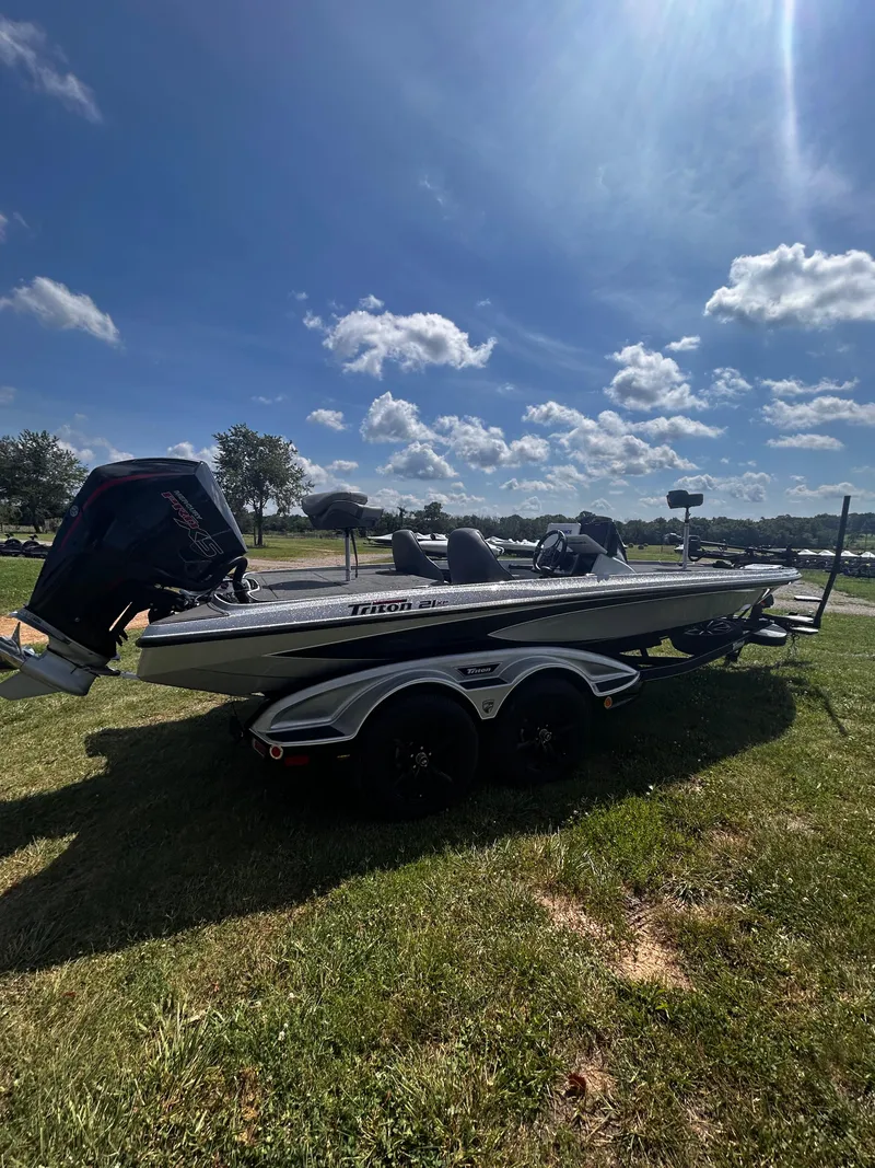 Slide: The Image of 2024 Triton 21XP boat on grass under a sunny sky with scattered clouds. - 20