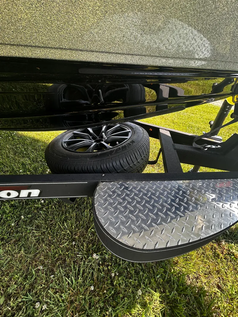 Slide: The Image of 2024 Triton 21XP trailer with black wheel and diamond plate step on grass. - 22