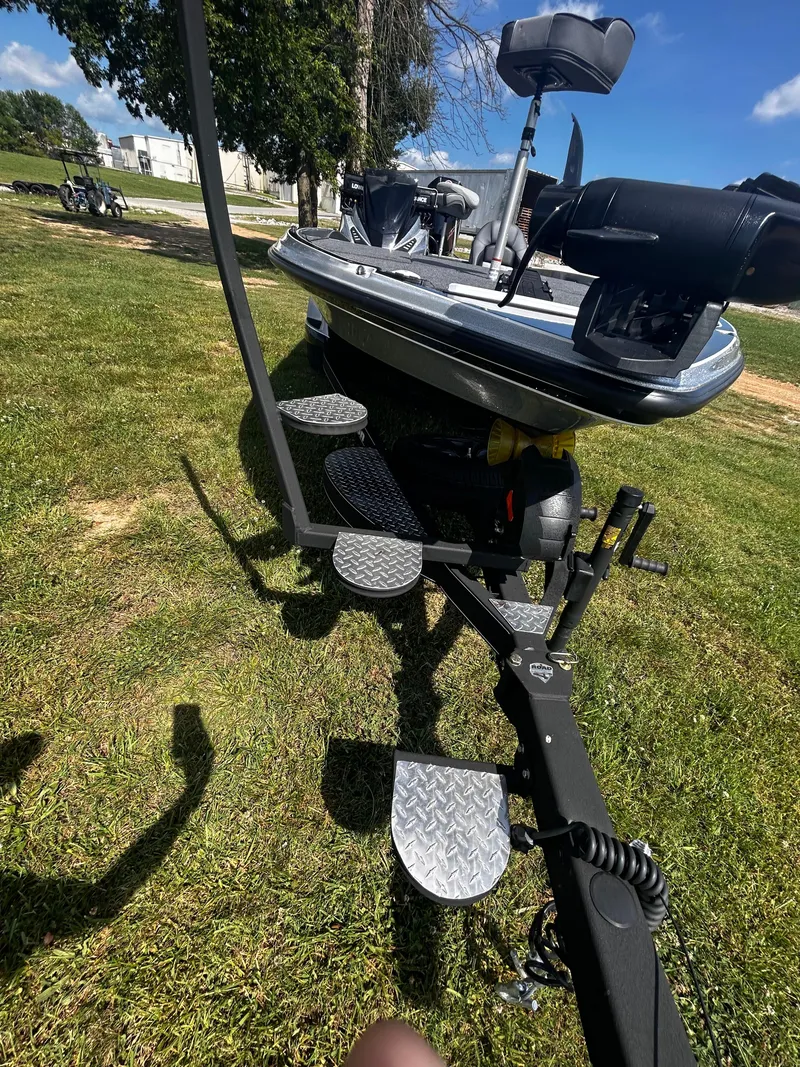 Slide: The Image of 2024 Triton 21XP boat on trailer, parked on grass under clear blue sky. - 23