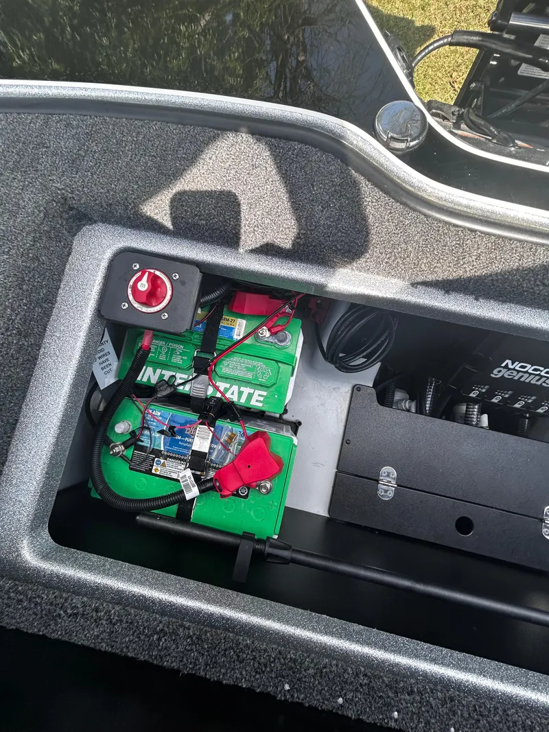 Slide: The Image of 2024 Triton 21XP boat battery compartment with Interstate batteries and Noco Genius charger. - 27
