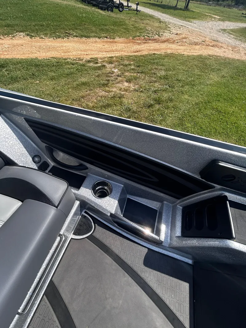 Slide: The Image of 2024 Triton 21XP boat interior with seating and storage compartments, set on grassy terrain. - 37