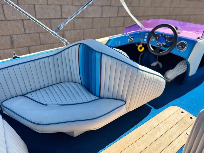 Slide: The Image of 1987 Bahner 19 BR boat interior with blue and white seating, wooden flooring, and steering wheel. - 16