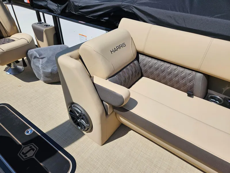 Slide: The Image of 2025 Harris Sunliner 230 boat interior with beige seating and speaker system. - 12