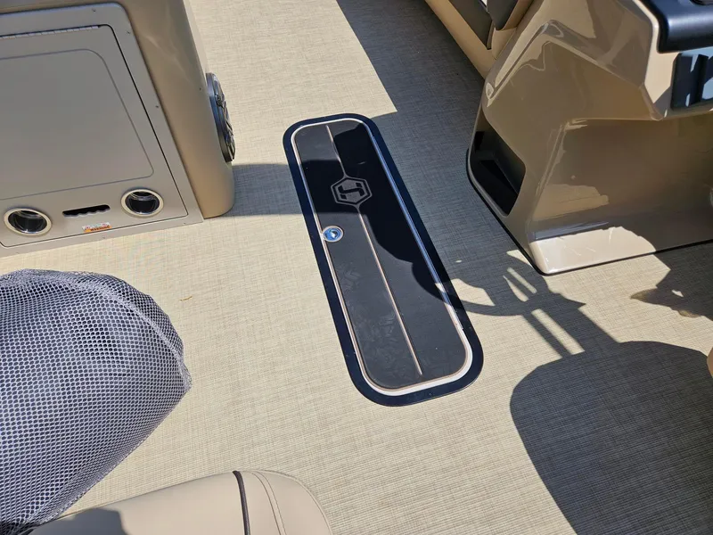 Slide: The Image of Interior of 2025 Harris Sunliner 230 boat with beige flooring and storage compartment. - 16