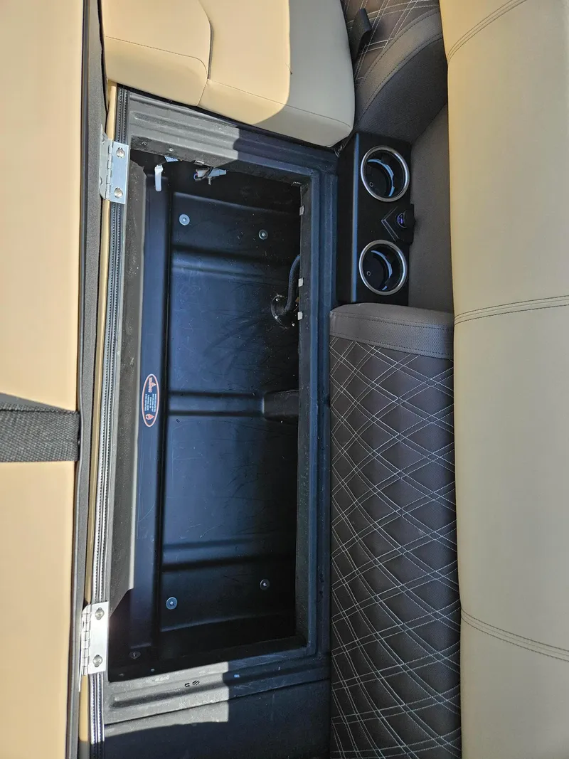 Slide: The Image of 2025 Harris Sunliner 230 interior storage compartment with cup holders and beige seating. - 18