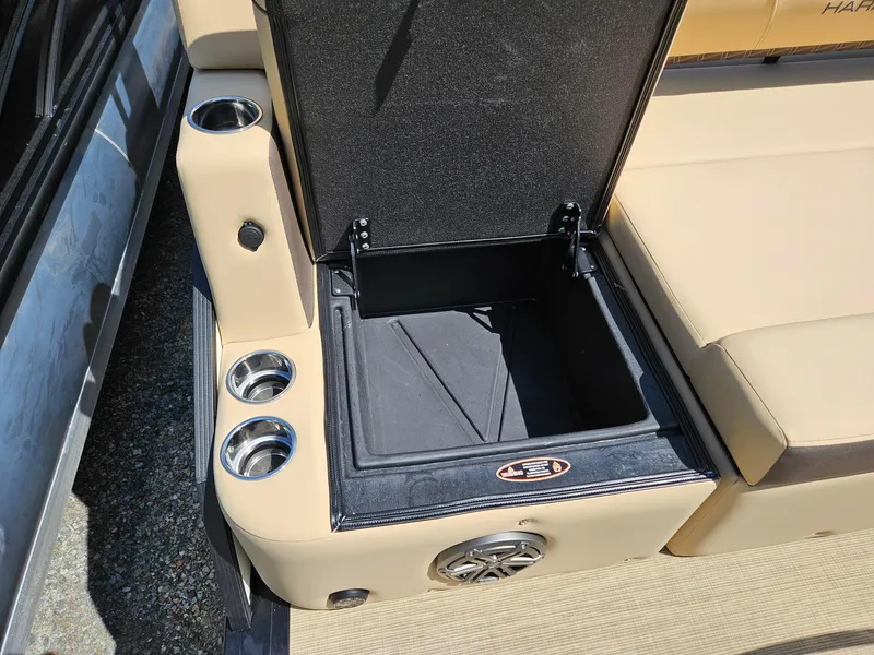 Slide: The Image of 2025 Harris Sunliner 230 boat interior with open storage compartment and cup holders. - 19