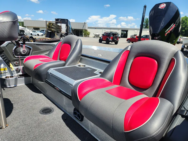 Slide: The Image of 2019 Ranger Z519L boat interior with red and black seats, parked outdoors. - 12