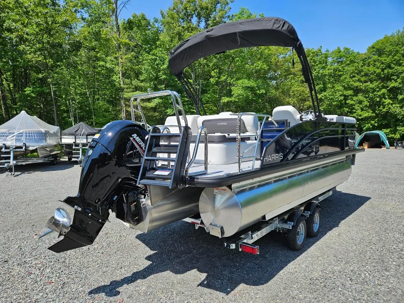 Slide: The Image of 2025 Harris Cruiser 210 pontoon boat with outboard motor in a wooded area. - 4