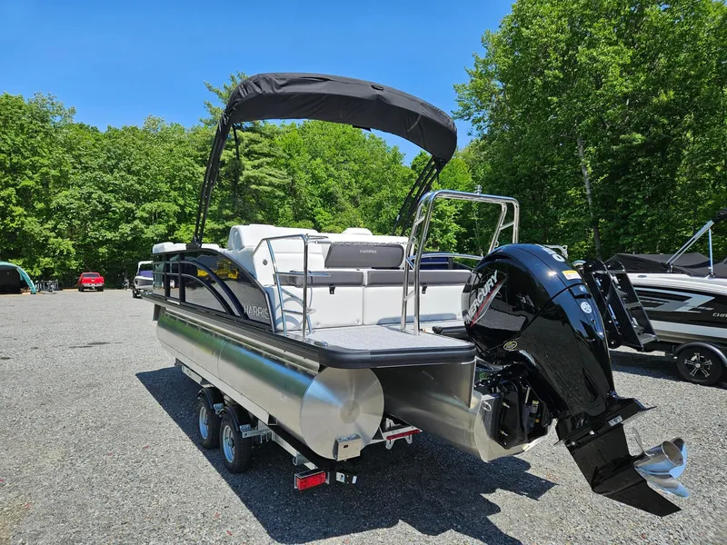 Slide: The Image of 2025 Harris Cruiser 210 pontoon boat with Mercury outboard motor in a wooded area. - 5