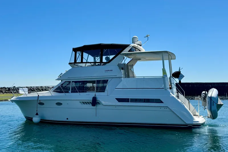 The Image of 1997 Carver 405 Aft Cabin Motoryacht cruising on calm waters under clear blue sky. - 0