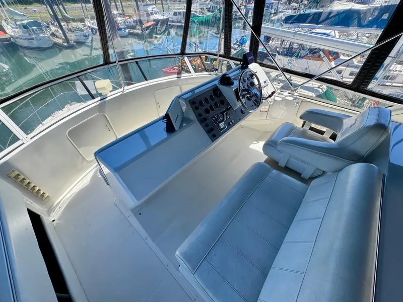 Slide: The Image of 1997 Carver 405 Aft Cabin Motoryacht helm with leather seating and marina view. - 10