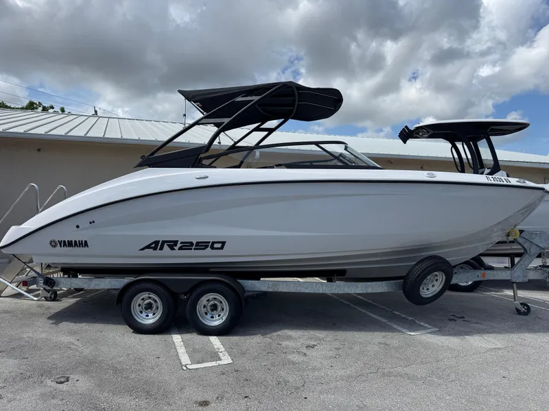 The Image of 2025 Yamaha AR250 boat on trailer, parked outdoors under cloudy sky. - 1