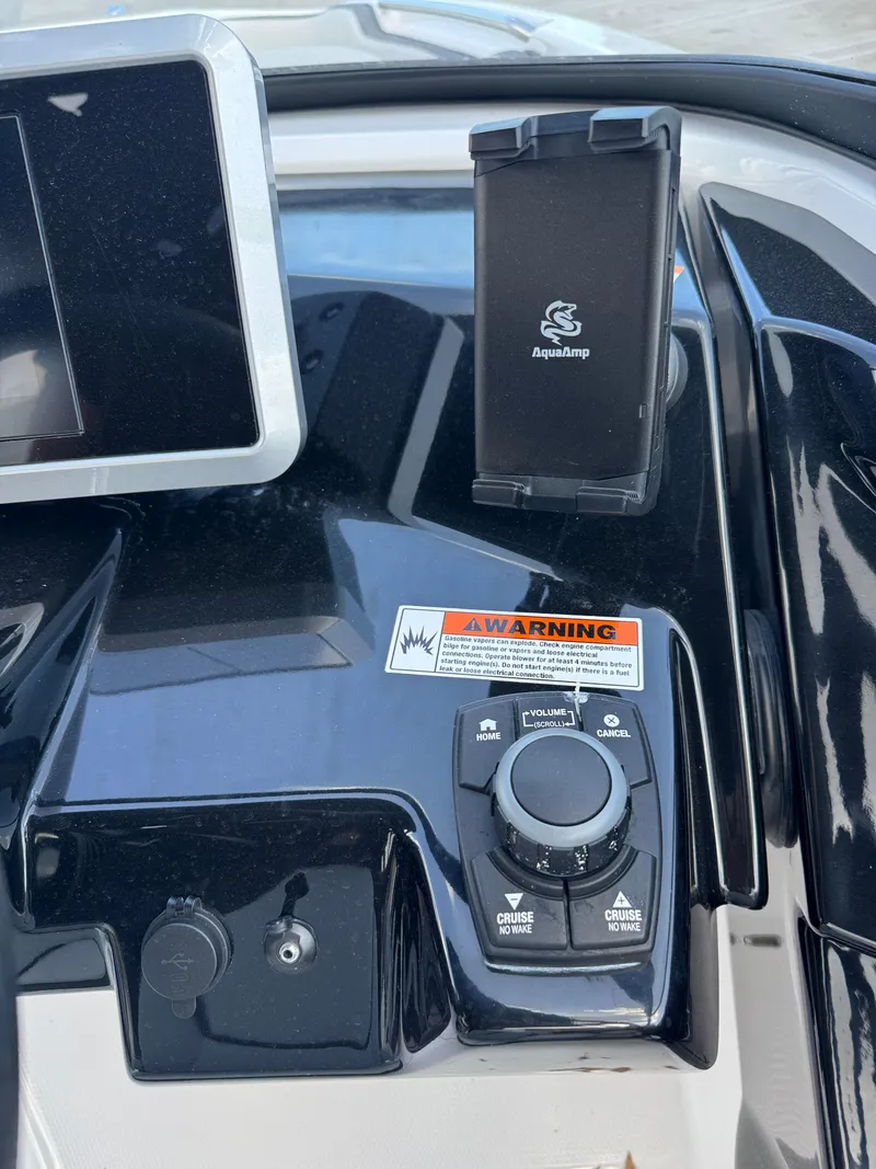 Slide: The Image of Control panel of 2025 Yamaha Boats AR250 with AquaAmp holder and warning label. - 19