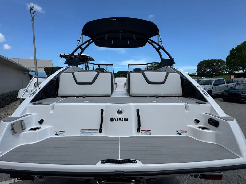 Slide: The Image of 2025 Yamaha Boats AR250, rear view, showcasing sleek design and spacious seating under a clear blue sky. - 2