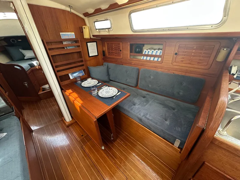 Slide: The Image of 1985 Sabre 34 MKI yacht interior with wooden dining area and blue cushioned seating. - 17