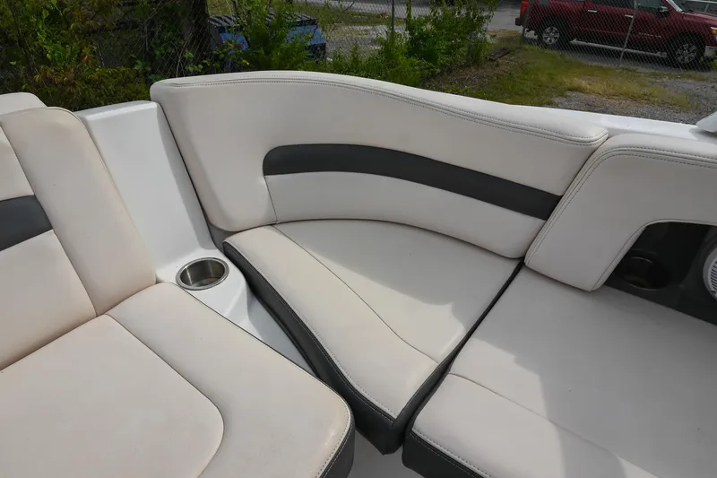 Slide: The Image of 2018 Chaparral 264 Sunesta boat interior with beige and black seating, cup holder visible. - 17