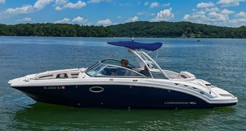 Slide: The Image of 2018 Chaparral 264 Sunesta boat on a serene lake with lush green shoreline. - 38