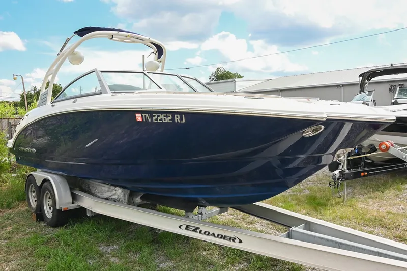 Slide: The Image of 2018 Chaparral 264 Sunesta boat on trailer, parked outdoors under a cloudy sky. - 6