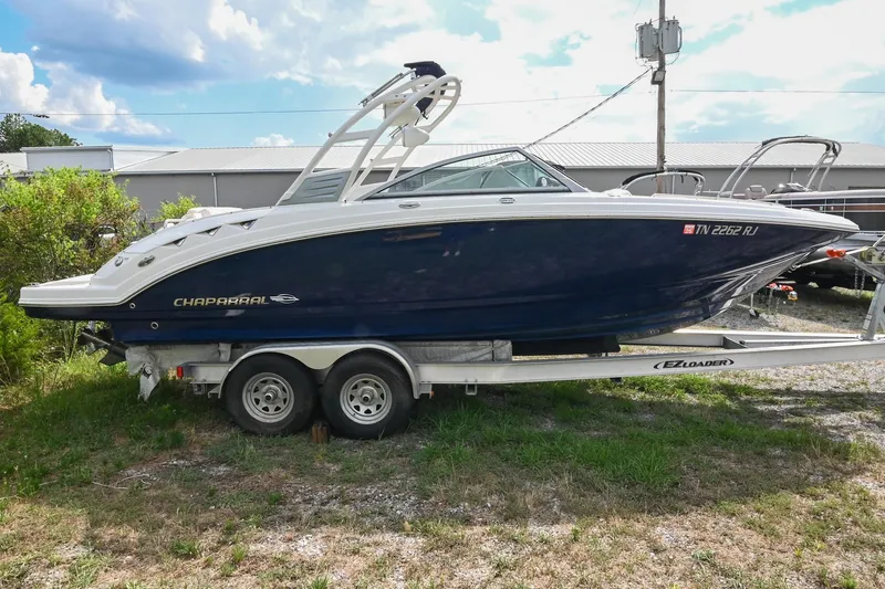 Slide: The Image of 2018 Chaparral 264 Sunesta boat on trailer, parked outdoors under a partly cloudy sky. - 7