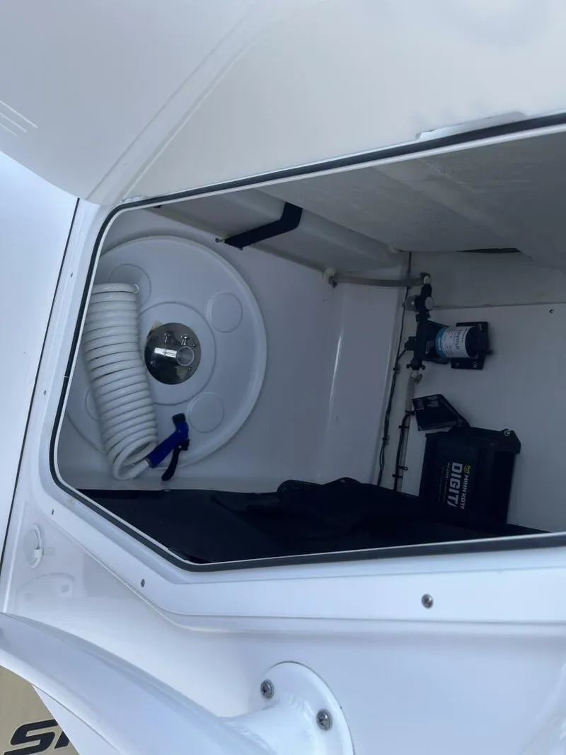 Slide: The Image of Storage compartment of a 2021 Sportsman 231 Heritage boat, featuring coiled hose and equipment. - 11