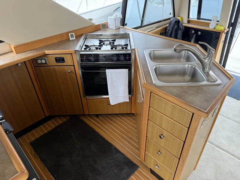 Slide: The Image of 2001 Bayliner 3988 Command Bridge Motoryacht kitchen with stove, sink, and wooden cabinetry. - 18