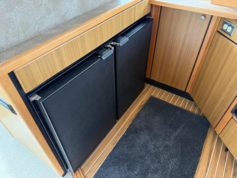 Slide: The Image of 2001 Bayliner 3988 Command Bridge Motoryacht interior with wood cabinetry and dual black fridge. - 19