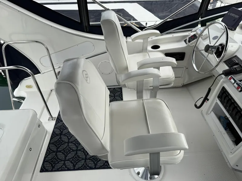 Slide: The Image of 2001 Bayliner 3988 Command Bridge Motoryacht helm with white captain chairs and steering wheel. - 43