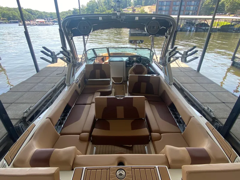 Slide: The Image of 2022 MasterCraft X26 boat interior with luxurious seating, docked by a scenic lake. - 12