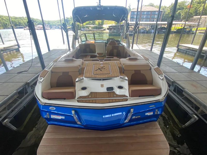 Slide: The Image of 2022 MasterCraft X26 boat docked, featuring spacious seating and sleek blue exterior. - 14