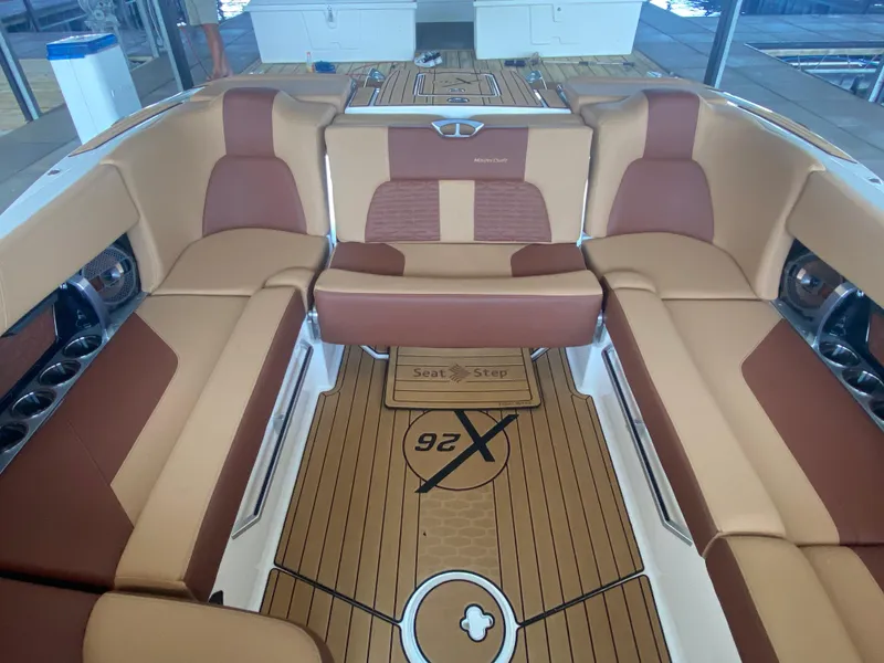 Slide: The Image of 2022 MasterCraft X26 boat interior with tan and brown seating, teak flooring. - 16