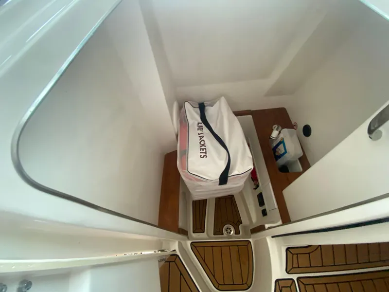 Slide: The Image of 2022 MasterCraft X26 interior storage with life jackets and wooden flooring. - 29