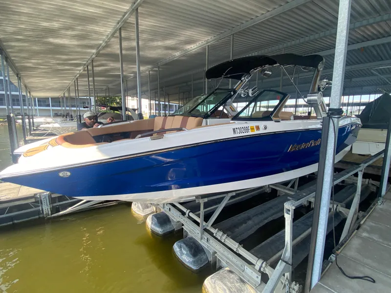 Slide: The Image of 2022 MasterCraft X26 boat in blue, docked under a covered marina. - 8