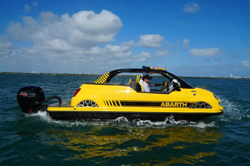 Slide: The Image of Yellow 2025 Fiat 500 Abarth boat hybrid on water, clear sky background. - 0