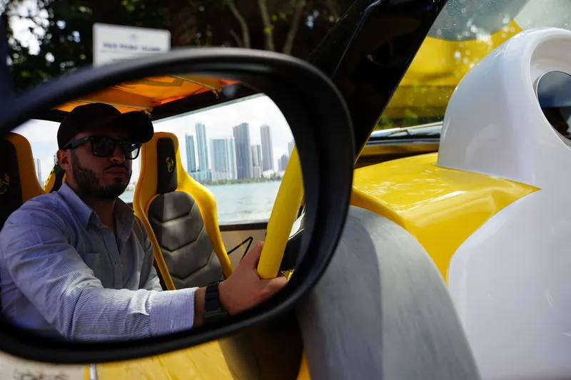Slide: The Image of Man driving 2025 Car Off-shore Fiat 500 Abarth, city skyline in background. - 17