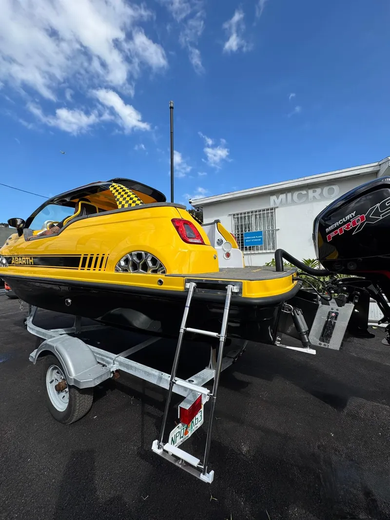Slide: The Image of Yellow Fiat 500 Abarth boat on trailer, 2025 model, under a blue sky. - 25