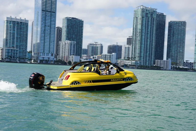 Slide: The Image of Yellow Fiat 500 Abarth boat on water with city skyline in background, 2025 model. - 5
