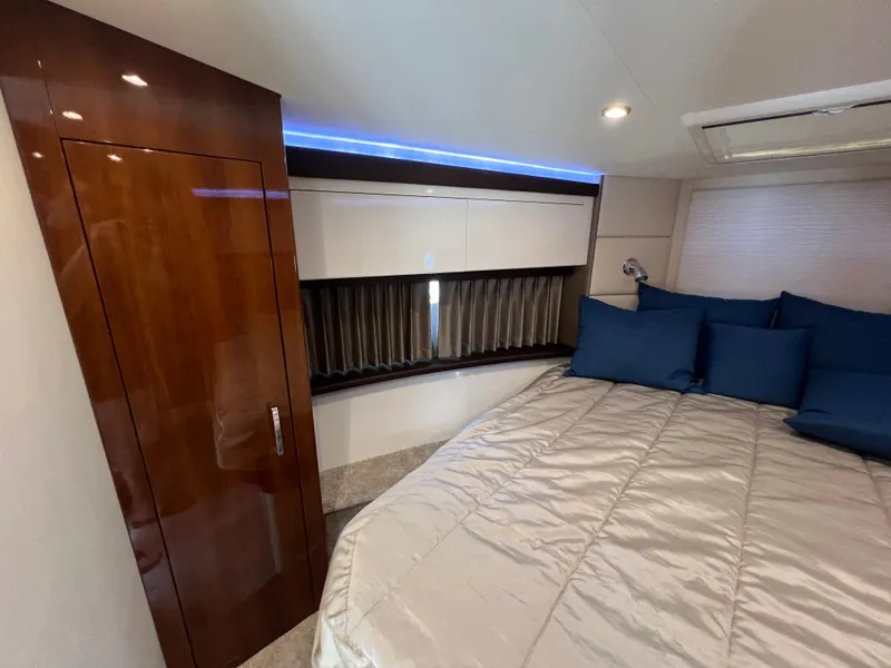Slide: The Image of Interior of 2016 Carver C34 Command Bridge with bed, blue pillows, and wooden cabinetry. - 18