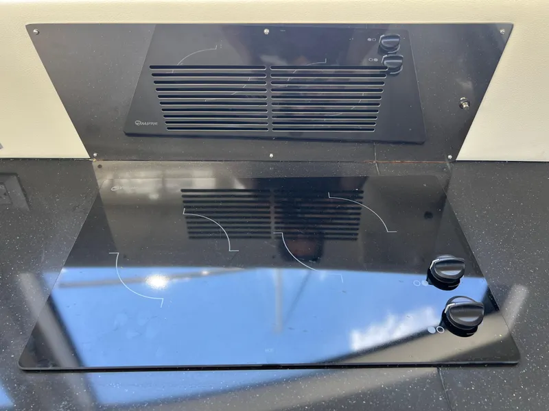 Slide: The Image of Stovetop on 2016 Carver C34 Command Bridge yacht, featuring sleek black design and control knobs. - 32