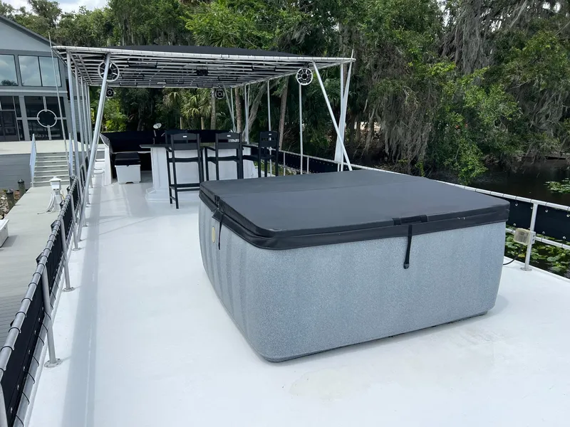 Slide: The Image of 1989 Sumerset houseboat deck with hot tub and seating area, surrounded by lush greenery. - 14