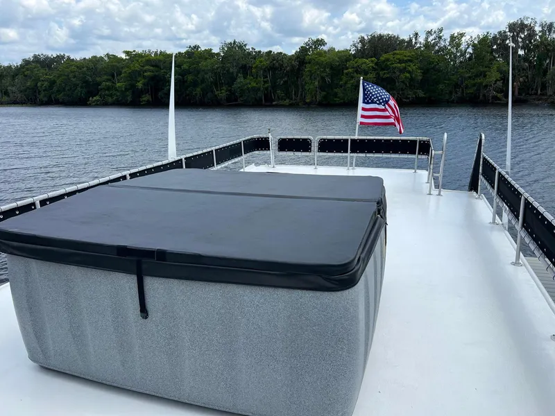 Slide: The Image of Rooftop deck of 1989 Sumerset Houseboat with hot tub and American flag, surrounded by water and trees. - 15